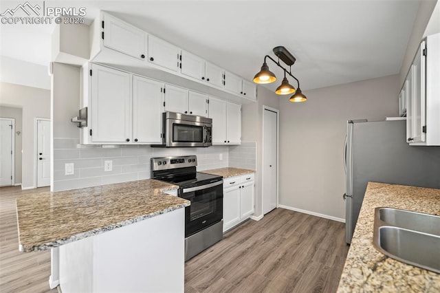 kitchen with stainless steel appliances, light wood-style flooring, backsplash, and white cabinetry