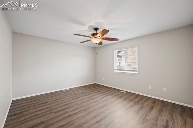 empty room with a ceiling fan, dark wood-style flooring, and baseboards