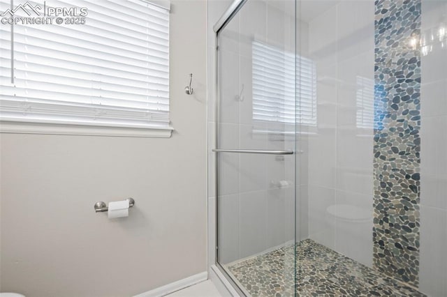 bathroom with a stall shower, toilet, and baseboards