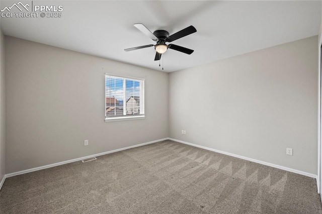 empty room with carpet floors, a ceiling fan, visible vents, and baseboards