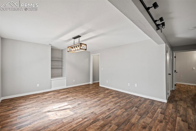 empty room featuring built in features, baseboards, and wood finished floors