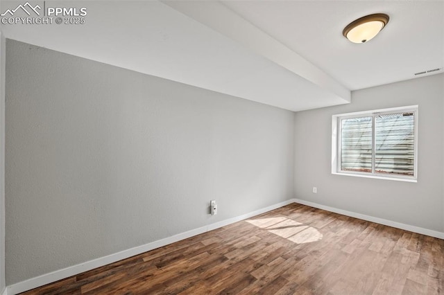 empty room featuring visible vents, baseboards, and wood finished floors