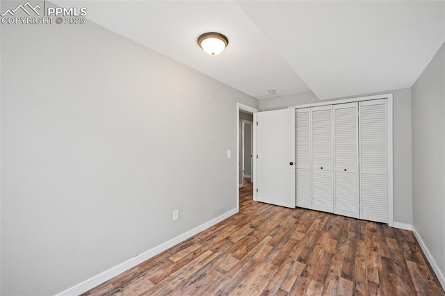 unfurnished bedroom with a closet, wood finished floors, and baseboards