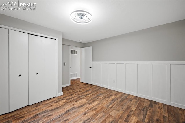 unfurnished bedroom featuring a closet, visible vents, and wood finished floors