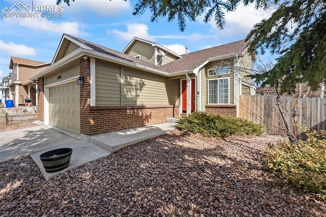 view of front facade featuring a garage, concrete driveway, brick siding, and fence