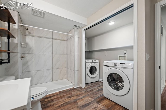 laundry area featuring laundry area, visible vents, dark wood-type flooring, and washing machine and clothes dryer