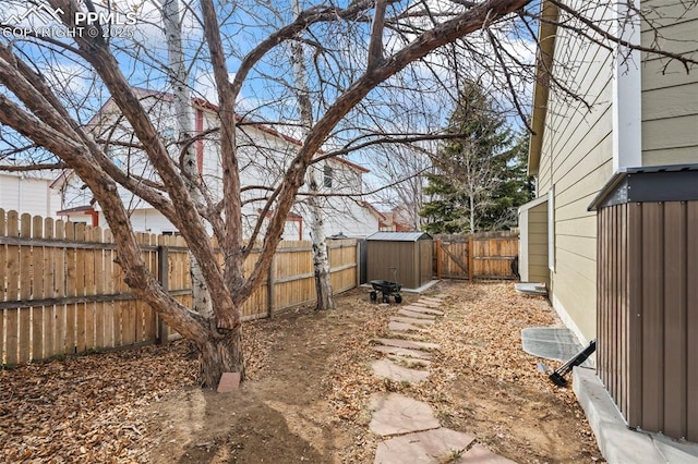 view of yard with a storage shed, a fenced backyard, and an outbuilding