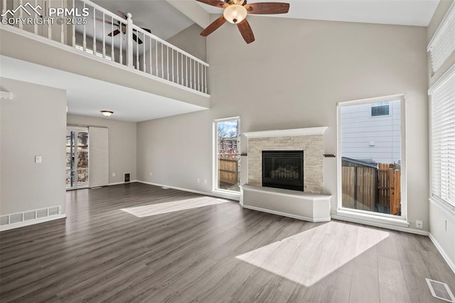 unfurnished living room with visible vents, wood finished floors, and a stone fireplace