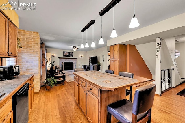 kitchen with tile countertops, light wood finished floors, a fireplace with raised hearth, ceiling fan, and dishwasher