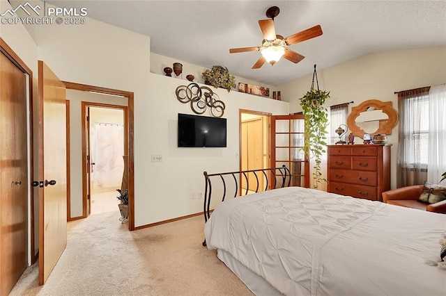 bedroom featuring lofted ceiling, light colored carpet, ensuite bathroom, a ceiling fan, and baseboards