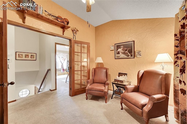 sitting room featuring carpet, french doors, a textured wall, vaulted ceiling, and an upstairs landing