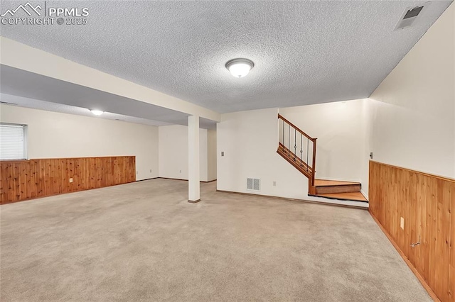 basement with wood walls, wainscoting, and visible vents