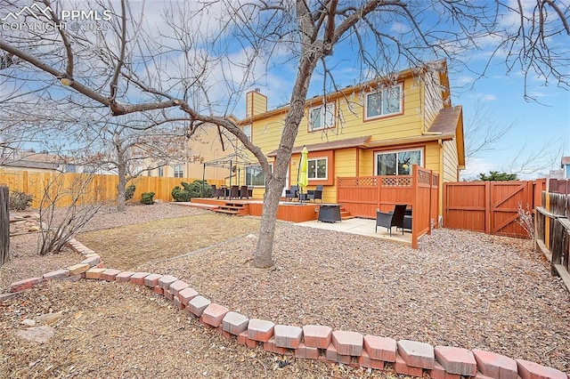 back of house with a chimney, a gate, a patio area, a deck, and a fenced backyard