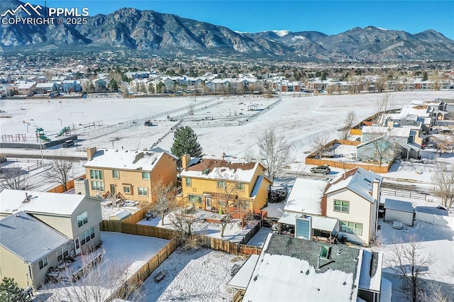 snowy aerial view with a mountain view and a residential view