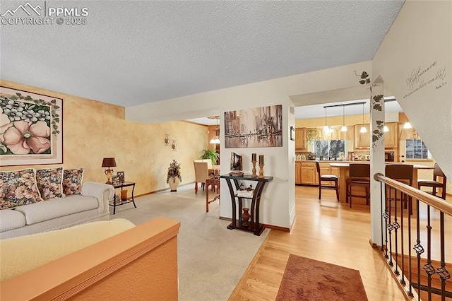 living area featuring baseboards, a textured ceiling, and light wood finished floors