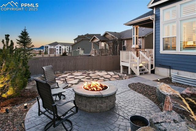 view of patio featuring an outdoor fire pit, fence, and a residential view