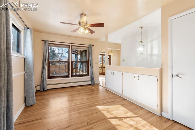 unfurnished room with light wood-type flooring, a baseboard radiator, arched walkways, and ceiling fan