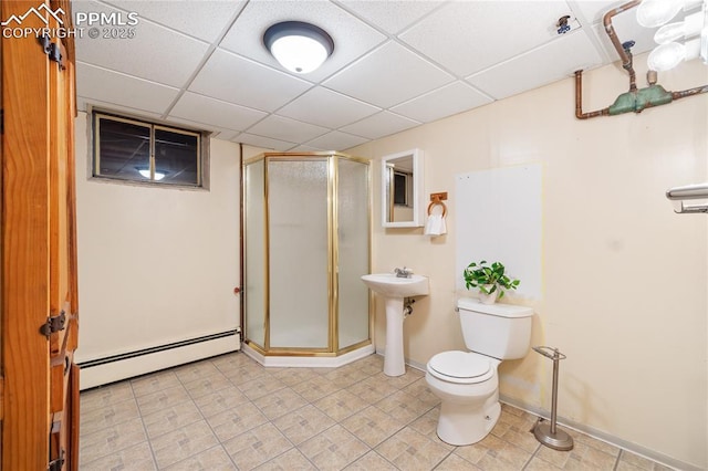 full bathroom featuring a drop ceiling, a baseboard radiator, toilet, a sink, and a stall shower