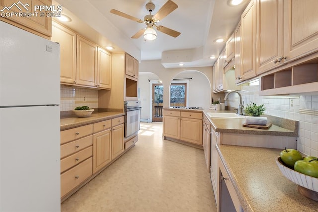 kitchen with arched walkways, light floors, light countertops, a sink, and white appliances