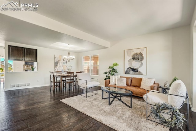 living room featuring a tray ceiling, dark wood-style flooring, visible vents, a chandelier, and baseboards