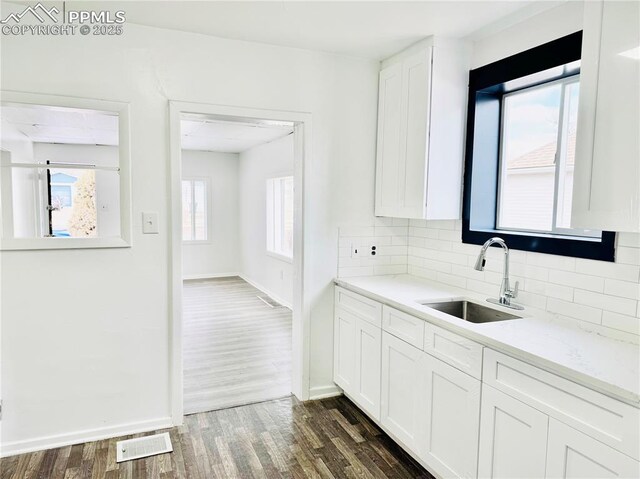 1108 W 16th St, Pueblo, CO 81003 - kitchen with dark wood-style flooring, backsplash, white cabinetry, a sink, and baseboards