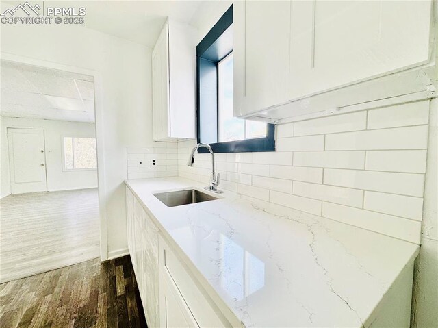 1108 W 16th St, Pueblo, CO 81003 - kitchen with dark wood finished floors, white cabinets, a sink, and decorative backsplash
