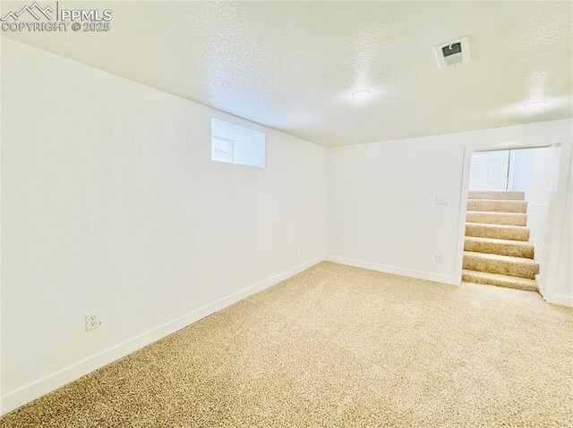1108 W 16th St, Pueblo, CO 81003 - below grade area with carpet floors, visible vents, stairway, a textured ceiling, and baseboards