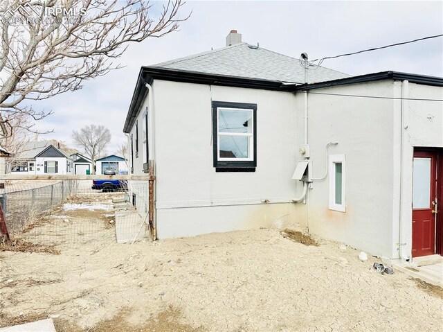 1108 W 16th St, Pueblo, CO 81003 - view of home's exterior with a shingled roof, fence, and stucco siding