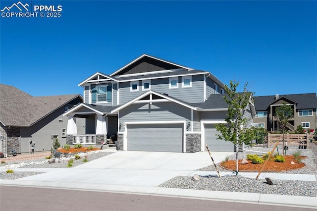 view of front of home with concrete driveway, covered porch, an attached garage, board and batten siding, and stone siding