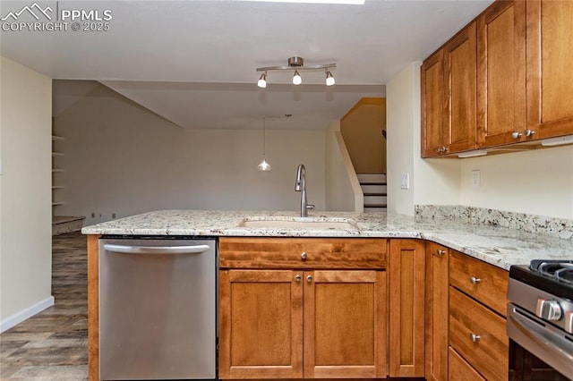 kitchen with a peninsula, appliances with stainless steel finishes, brown cabinetry, and a sink