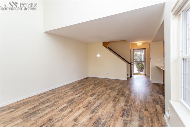 unfurnished room with stairway, baseboards, and wood finished floors