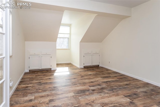 bonus room with dark wood-style floors, lofted ceiling, and baseboards