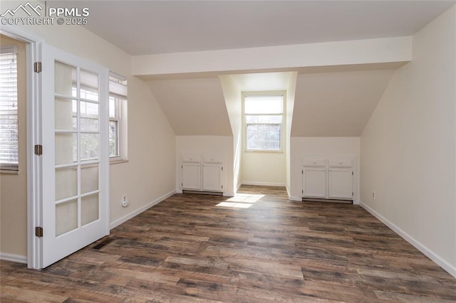 additional living space with dark wood-style floors, visible vents, vaulted ceiling, and baseboards