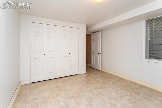 unfurnished bedroom with baseboards and a closet