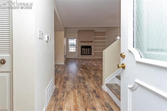 foyer featuring stairway, a fireplace, visible vents, and wood finished floors