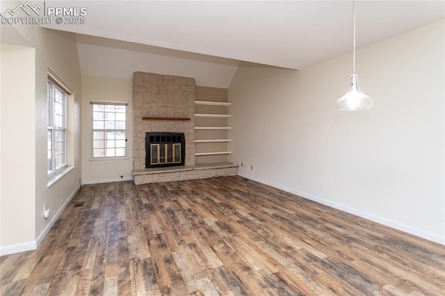 unfurnished living room featuring a fireplace, baseboards, and wood finished floors