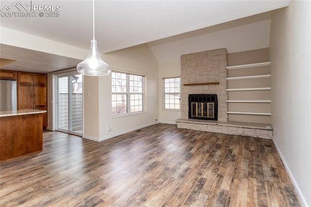 unfurnished living room featuring lofted ceiling, a fireplace, baseboards, and wood finished floors