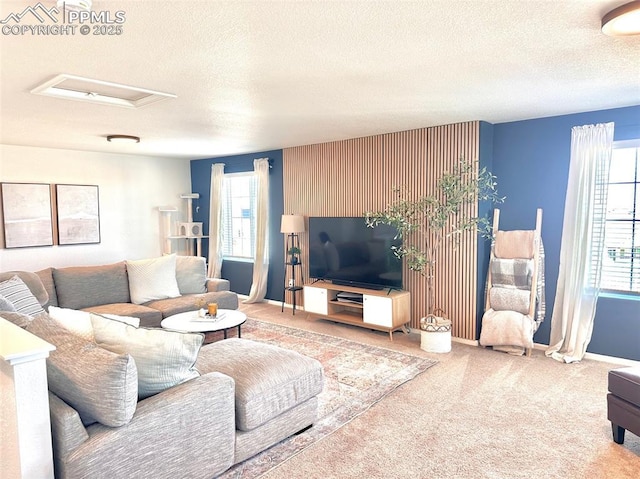 living room featuring attic access, carpet, a textured ceiling, and baseboards