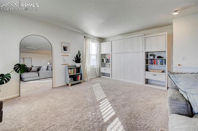 interior space with arched walkways, carpet flooring, and baseboards