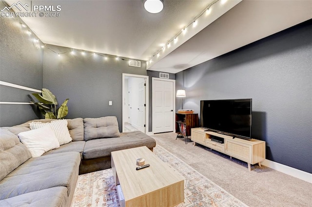 living area with light carpet, a textured wall, visible vents, and baseboards