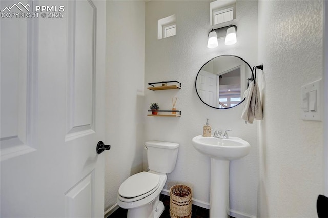 bathroom with a sink, toilet, and baseboards