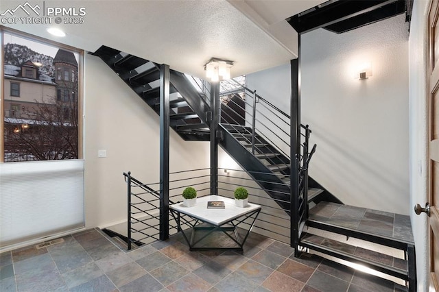 stairs with stone finish floor and visible vents