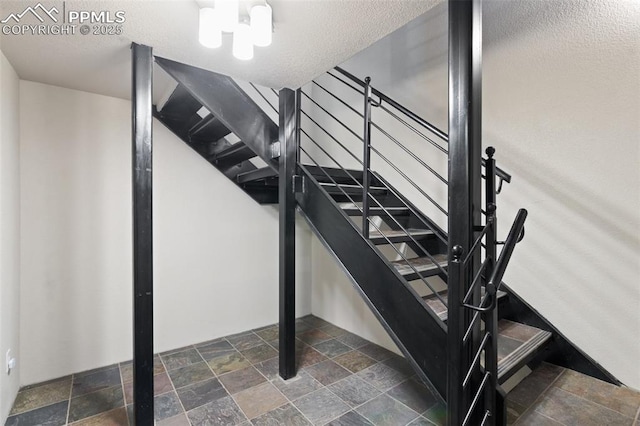 stairway with stone tile flooring and a textured ceiling