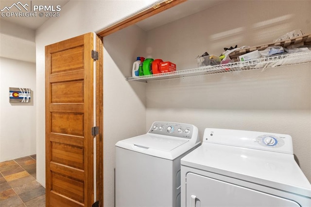 washroom featuring laundry area, washer and clothes dryer, and stone finish floor