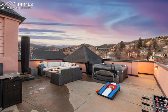 patio terrace at dusk with a residential view, a mountain view, and an outdoor living space with a fire pit