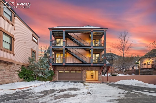 view of front of home featuring a garage, stairway, and a balcony