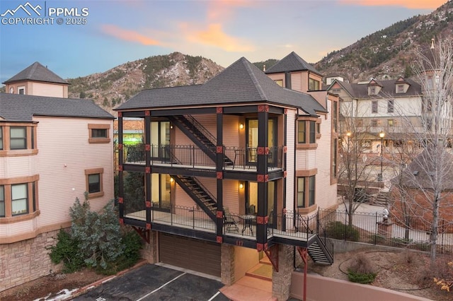 view of front of house with a mountain view, a balcony, a garage, driveway, and stairway