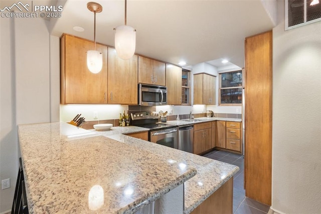 kitchen with a peninsula, dark tile patterned floors, visible vents, appliances with stainless steel finishes, and decorative light fixtures