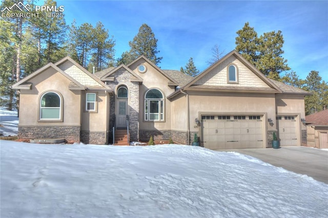 view of front of property featuring stone siding, an attached garage, and stucco siding