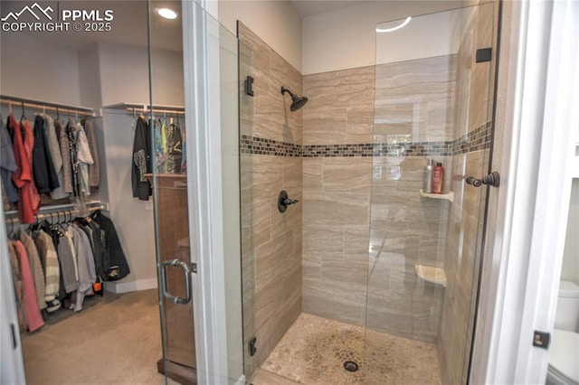 bathroom with a walk in closet, a shower stall, and toilet